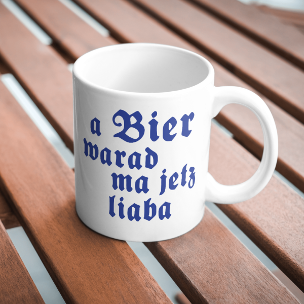 Weiße Keramiktasse mit blauem bayerischen Spruch „A Bier warad ma a liaba“ – Frontalansicht