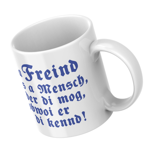 Schrägansicht der weißen Keramiktasse mit dem bayerischen blauen Spruch „A Freind is a Mensch“