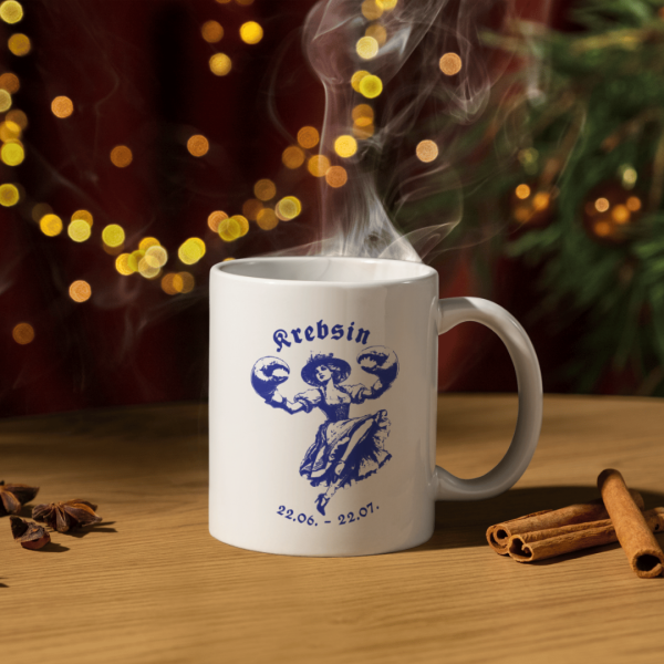 Weiße Keramiktasse Sternzeichen Krebs, umgeben von Weihnachtsdekoration und einer gemütlichen Winteratmosphäre