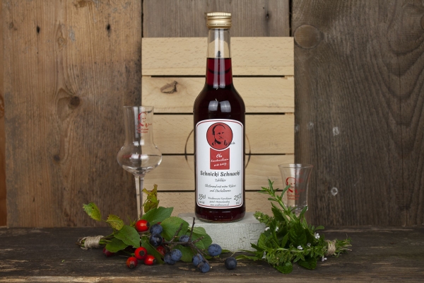 "Ein Glas Schnicki Schnacki Schnaps auf rustikalem Holztisch – jetzt bei Woidladinger.de erhältlich"