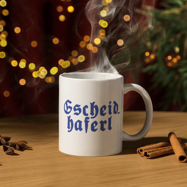 Bayerische Keramiktasse „Gscheidhaferl“ auf Holztisch mit dampfendem Kaffee