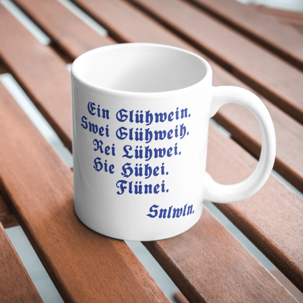 Bayerische Keramiktasse mit Glühwein-Spruch, dekorativ auf einem winterlichen Tisch mit Glühwein