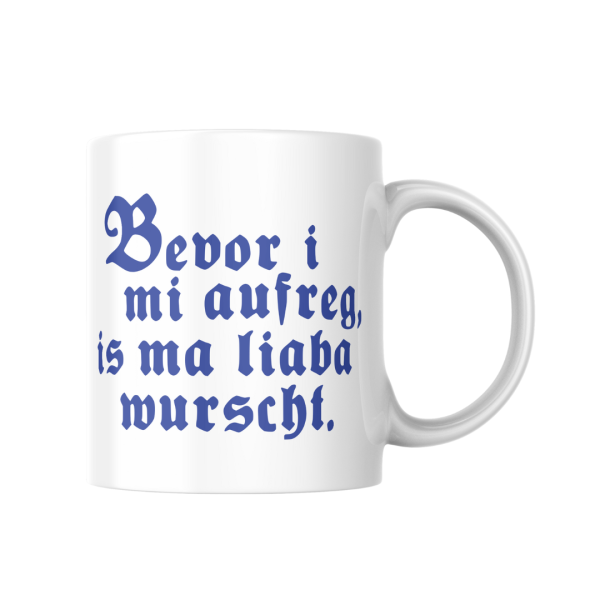 Weiße Keramiktasse mit bayerischem Spruch „Bevor i mi aufreg, is ma liaba wurscht“, perfekte Geschenkidee.