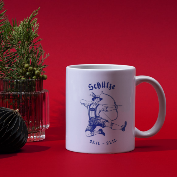 Weiße Keramiktasse mit Schütze Motiv auf einem festlich gedeckten Weihnachtstisch